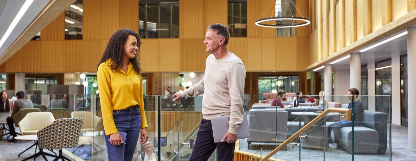 Two members of staff stand chatting inside the Nexus innovation hub at Leeds University