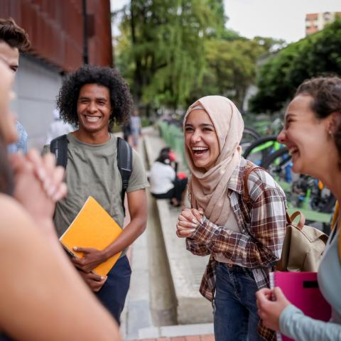 A group of students on campus chatting and laughing