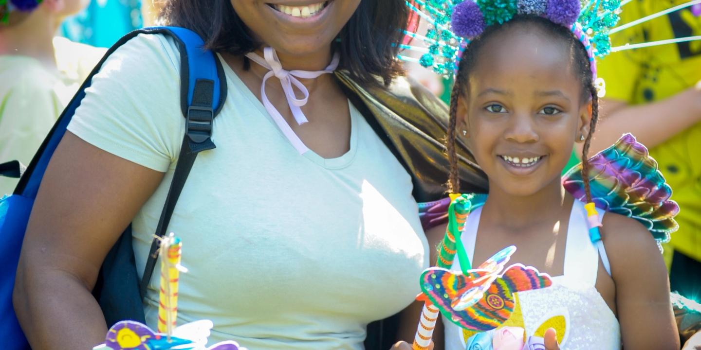 A mother and child wearing carnival costumes stand smiling at an arts event in Warwick